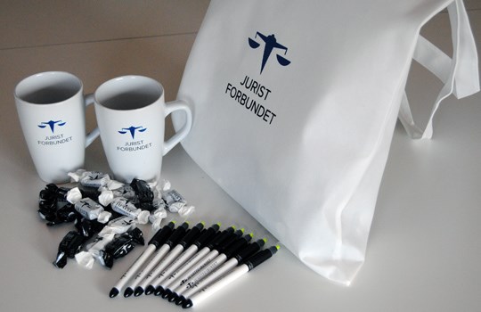 Vervepakke med kopper, karameller, penner og nett - preget med Juristforbundets logo.